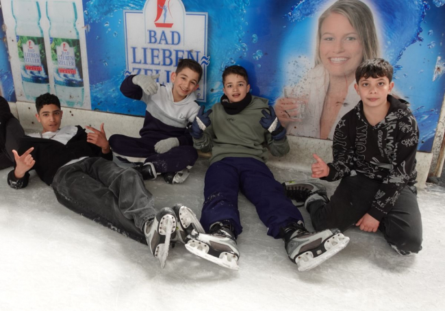 Schüler sitzen gemütlich auf dem Eis.